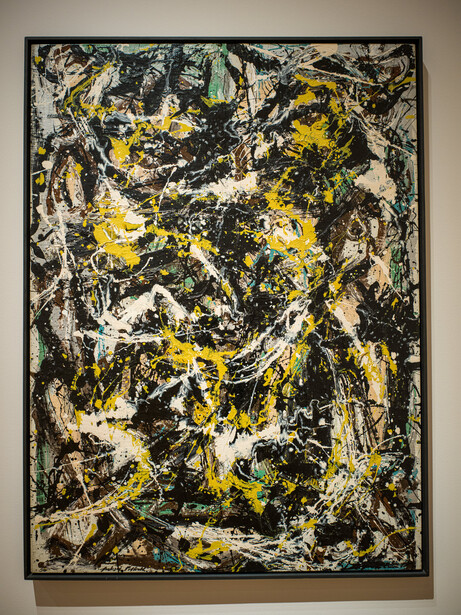 Abstract painting with gestural black lines, splatters, and drips across cream, yellow, and green backgrounds.
