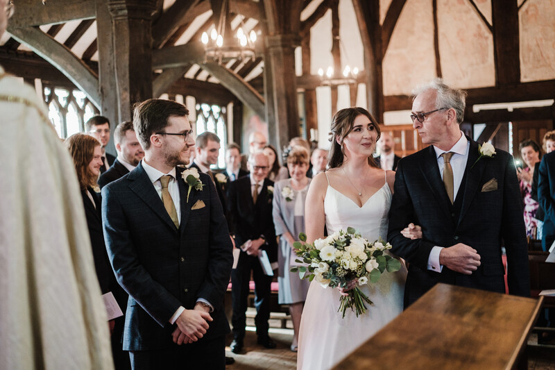 Bride walking down the aisle with her father during a church wedding ceremony.