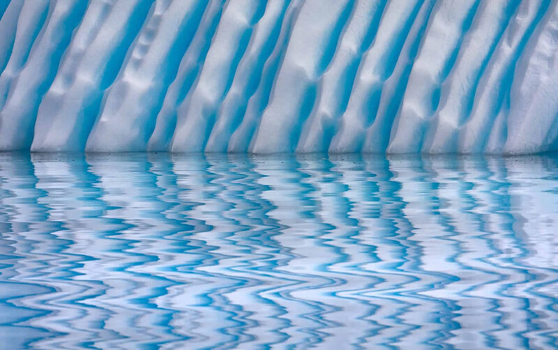 Swimming pool with water ripples reflecting striped blue and white overhead structure.