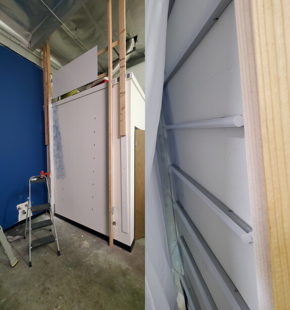 DIY backdrop stand constructed with wooden framing and white foam core panels in an indoor studio space.