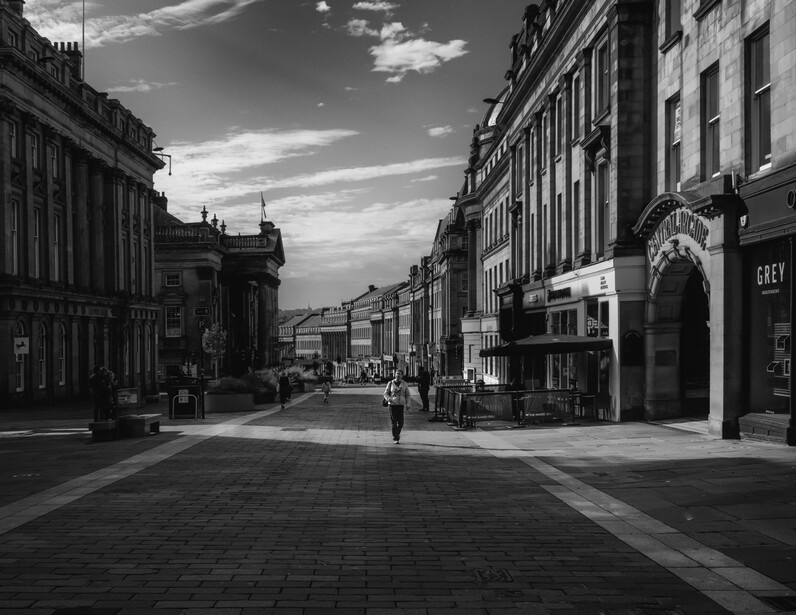 Black and white street photograph of a European city street with classical architecture and dramatic sky.