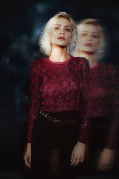 Woman in burgundy knit sweater with double exposure effect creating a ghosted silhouette behind her.