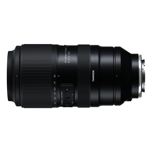 Black telephoto zoom lens with textured grip and focusing ring, mounted horizontally against white background.