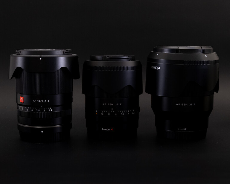 Three black camera lenses arranged side by side against a dark background.