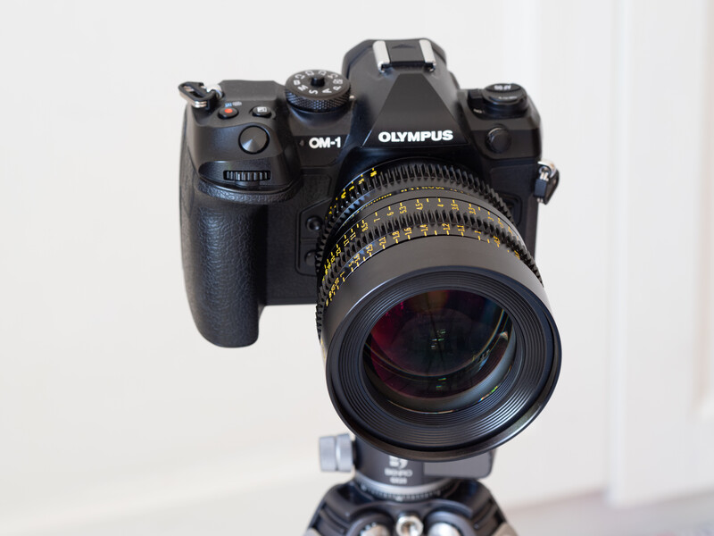 Olympus OM-1 film camera with telephoto lens mounted on tripod head.