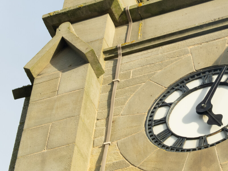 Close-up of a stone clock tower showing a large circular clock face and architectural masonry details.