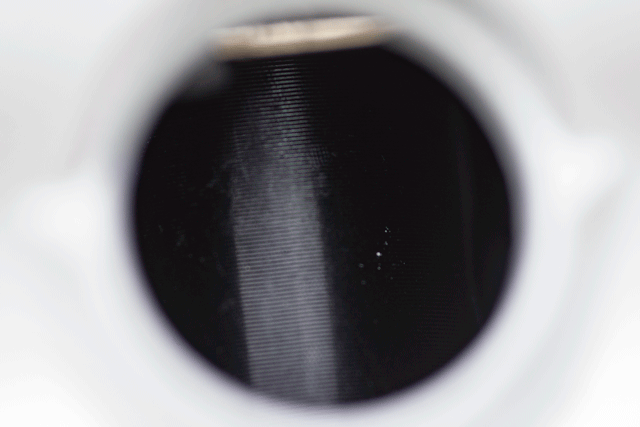 Close-up macro photograph of a camera lens aperture mechanism showing concentric metal blades in fully closed position.