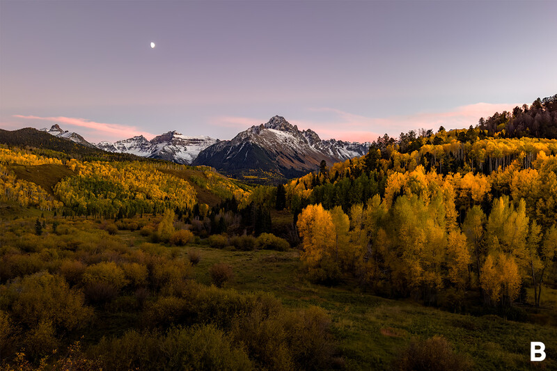 Mountain valley at twilight with golden aspens in foreground and snow-capped peaks beneath purple sky.