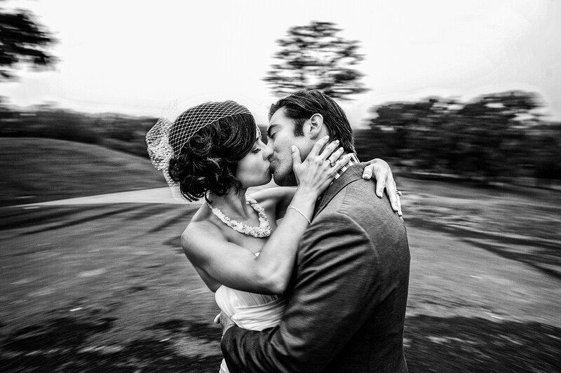 Bride and groom kissing while moving, captured with motion blur in black and white.
