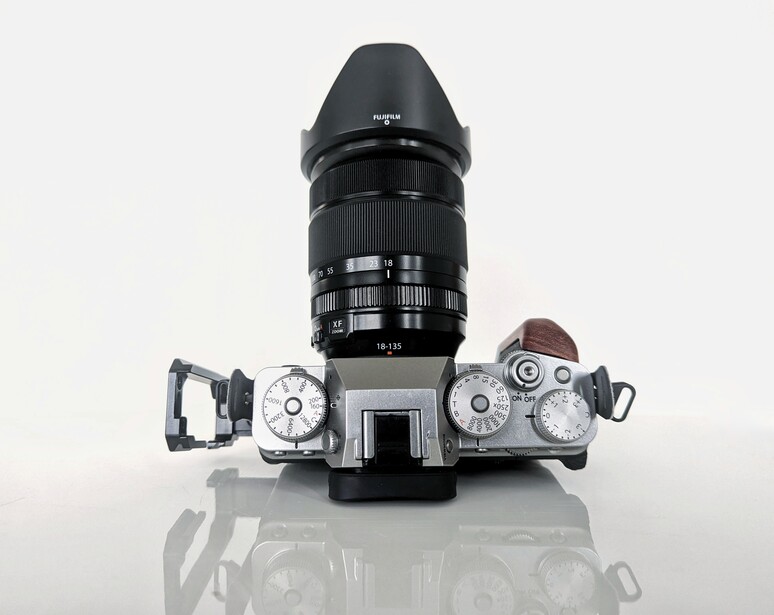 Top-down view of a silver rangefinder camera with black lens and hood, flanked by two light meters.