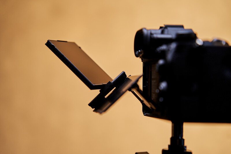 Camera mounted on tripod with articulating monitor arm extended toward lens.