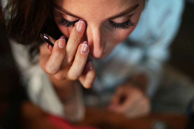 Woman on phone with hand near face, soft natural lighting and shallow depth of field.