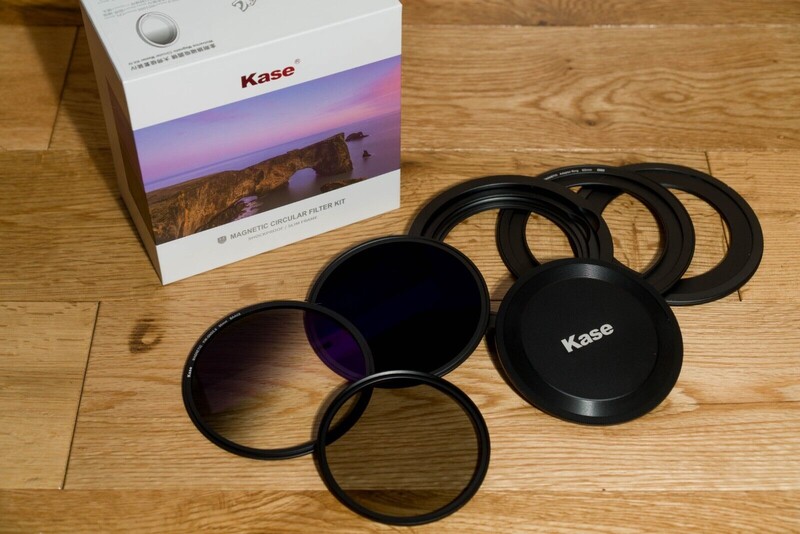 Kase filter kit displaying circular glass filters, lens caps, and protective carrying box on wooden surface.