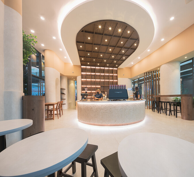 Modern cafe interior with curved counter, warm ambient lighting, and minimalist seating arrangement.