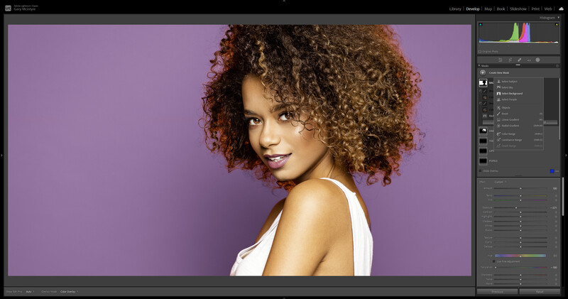 Woman with curly auburn hair against vibrant purple background in studio portrait.