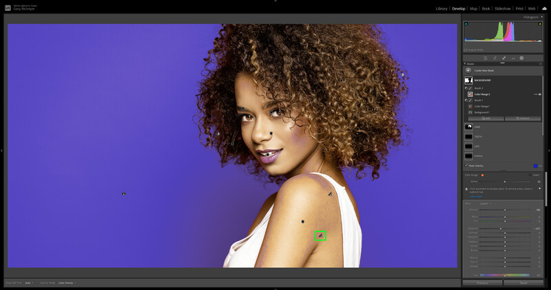 Portrait of a woman with voluminous curly hair against a vibrant purple background.