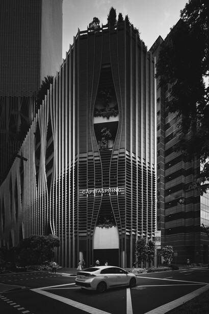 Black and white architectural photograph of a tall modernist building facade with vertical ribbed lines and a symmetrical central opening.