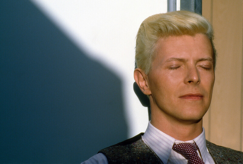 Man with blonde hair wearing a light purple shirt and patterned tie, photographed indoors with soft directional lighting.