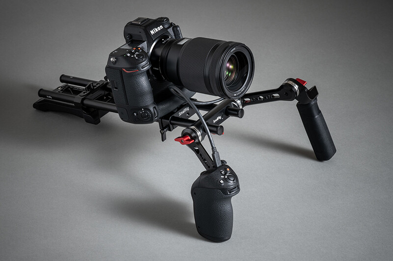 Nikon DSLR camera mounted on a black shoulder rig with follow focus and remote handle.