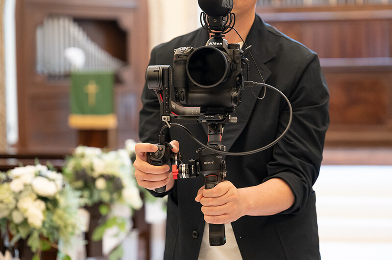 Videographer holding a cinema camera with gimbal stabilizer rig in an indoor setting.