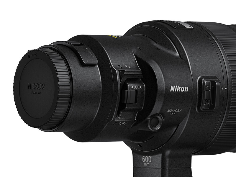 Nikon telephoto lens with focus motor and accessories mounted on a tripod collar.