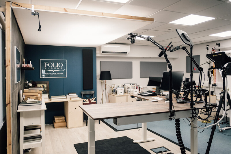 Modern photography studio with workstation, lighting equipment, and teal accent wall with FOLIO signage.