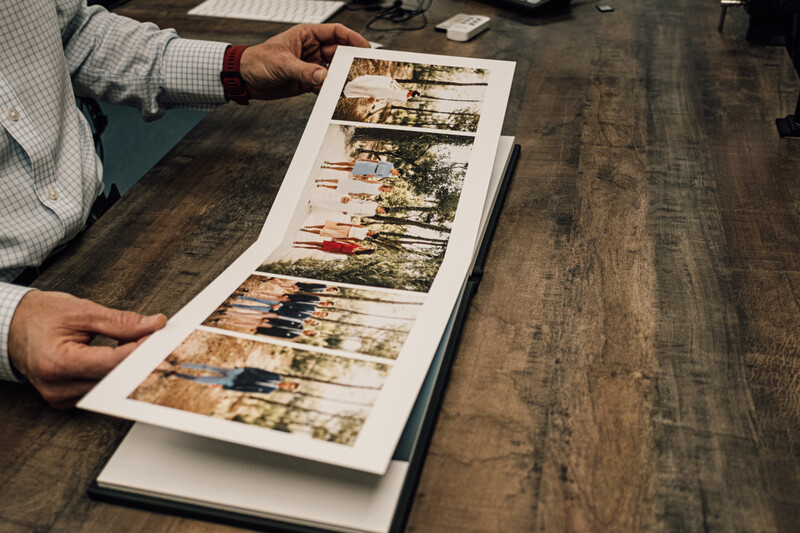 Photographer holding open a contact sheet with multiple color photographs arranged in rows.