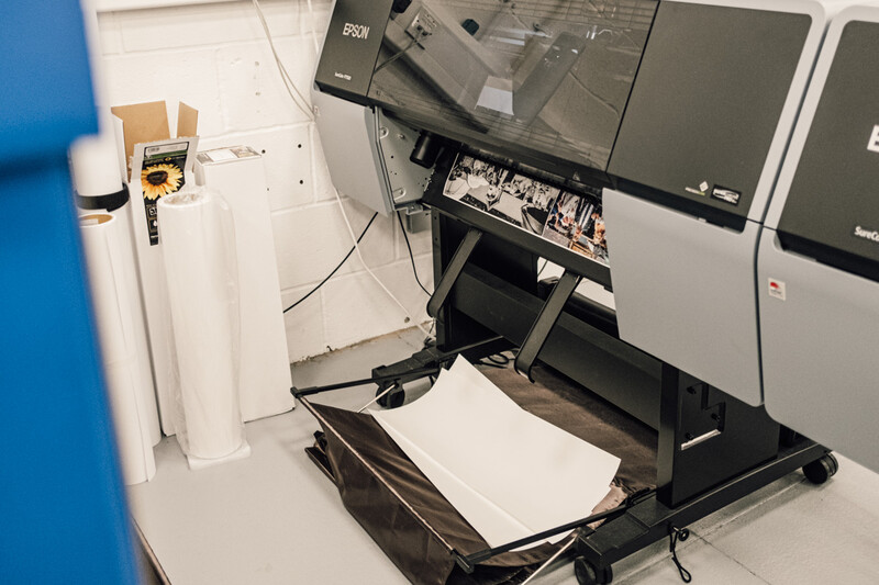 Large format medical or laboratory analyzer with open output tray showing white paper output sheets.