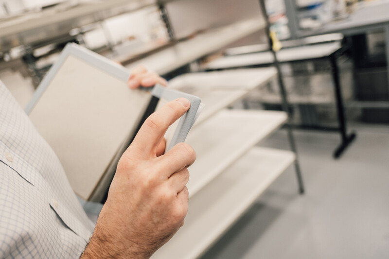 Man's hand holding a tablet device in a modern office or studio environment.