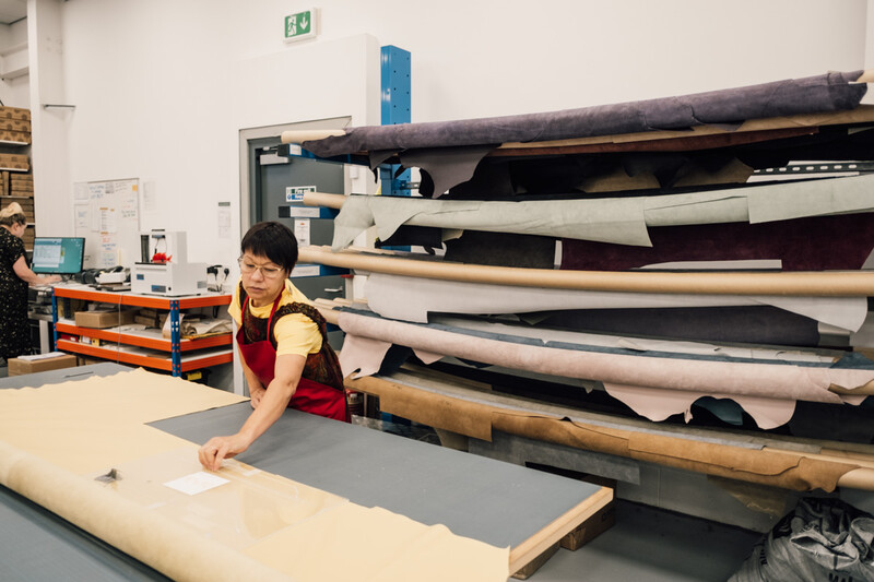 Craftsperson working with large format materials in a studio with organized storage racks.
