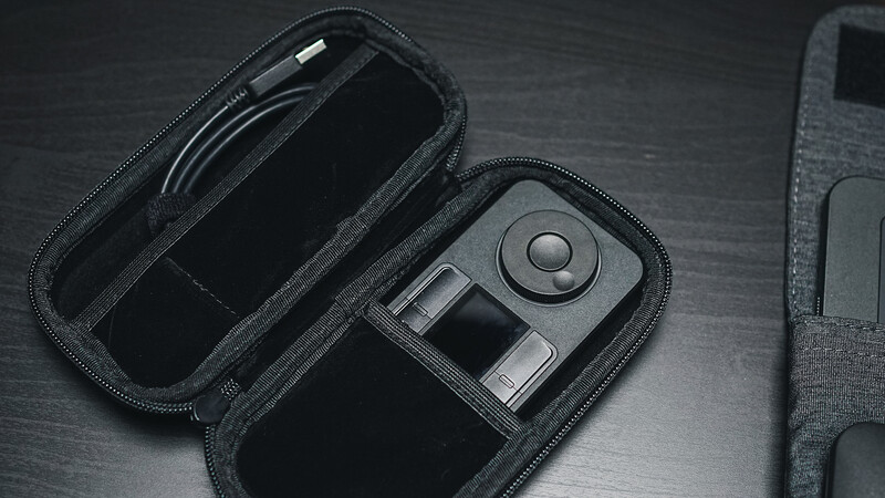 Open camera gear case displaying a remote control and camera accessory on dark wood surface.