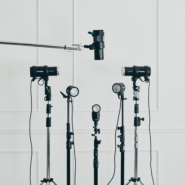 Professional lighting kit with five mounted softboxes and one overhead boom light against white backdrop.