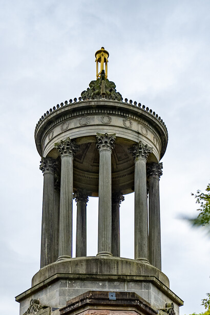 Classical stone monument with Corinthian columns and a domed cupola topped with a gilt statue.