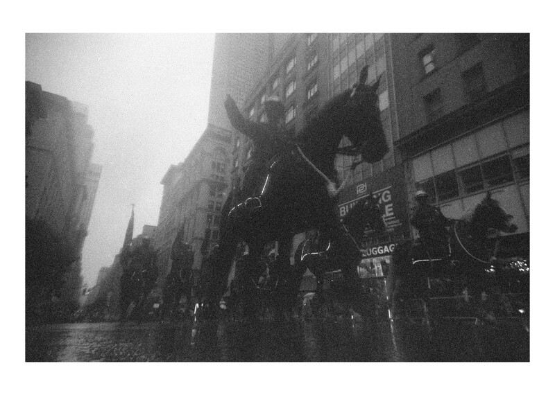 Silhouetted equestrian statue on an urban street lined with tall buildings.
