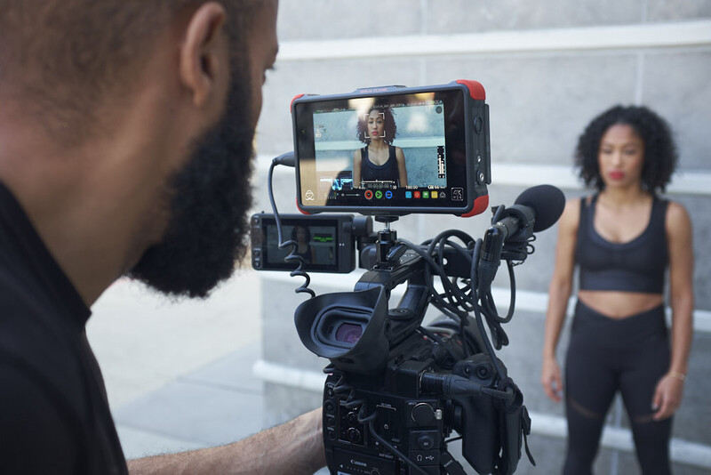 Filmmaker operating a professional camera with external monitor displaying live video feed of talent.