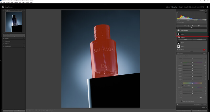 Red fragrance bottle with black cap photographed against a blue gradient background with dramatic lighting.
