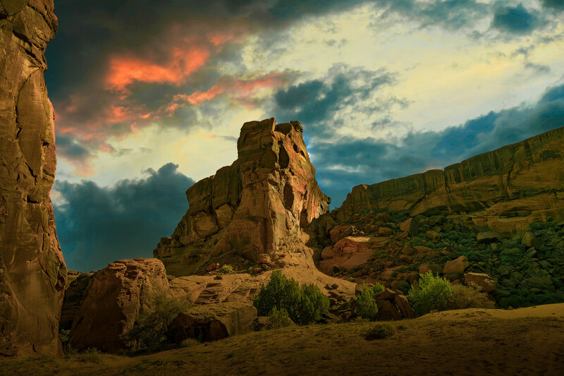 Dramatic desert landscape with towering rock formations under a golden sunset sky with storm clouds.