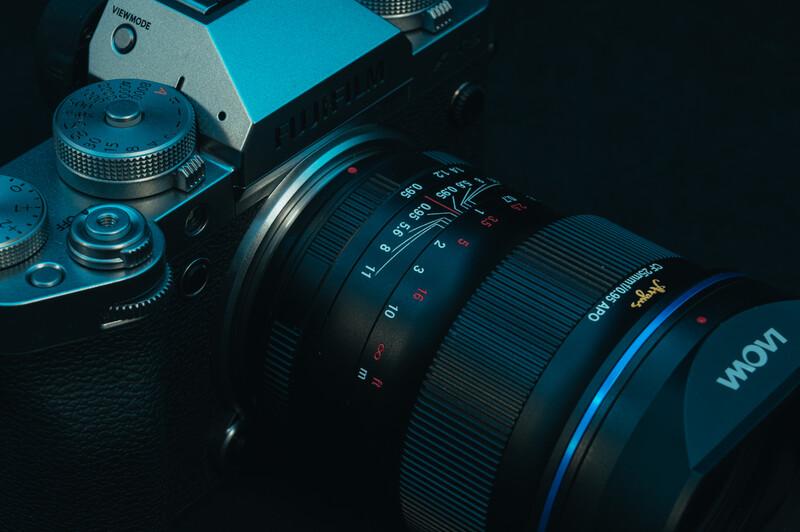 Camera with multiple lenses arranged on dark surface, lit with blue tones.