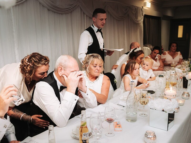 Wedding reception guests seated at a long table during a formal dinner service.
