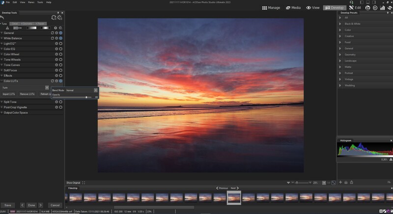 Screenshot of photo editing software displaying a vibrant sunset landscape with warm orange and pink tones reflected on water.