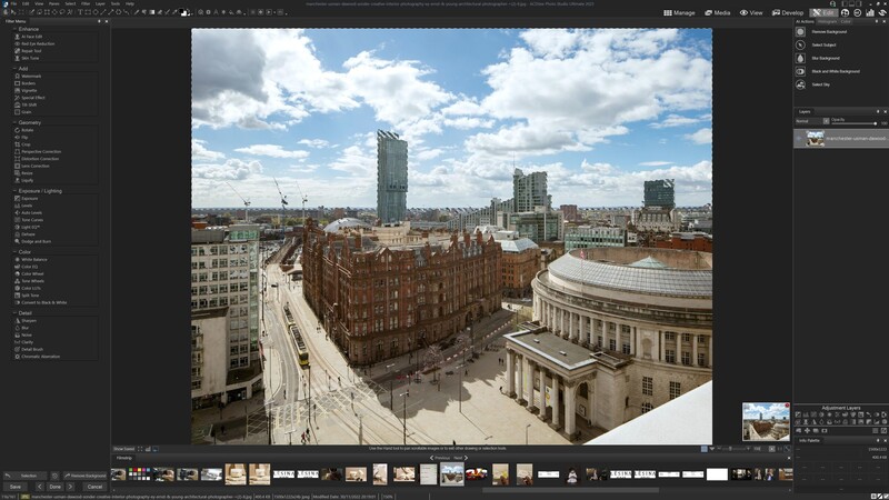 Urban cityscape viewed from elevated vantage point showing curved brick building, modern towers, and classical stone structure under partly cloudy sky.