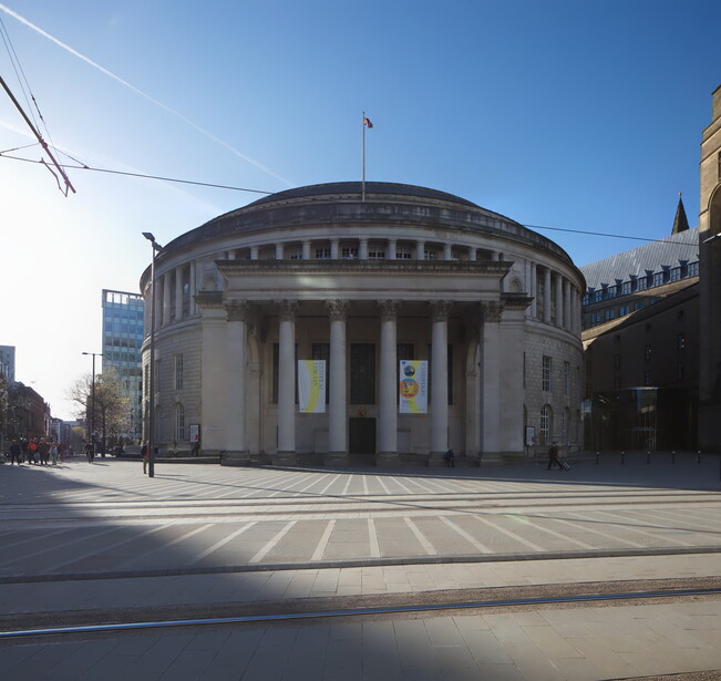 Neoclassical domed building with columned portico and symmetrical facade in urban plaza.
