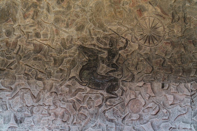 Ornate stone relief carving depicting a figure on horseback amid intricate scrollwork and decorative patterns.