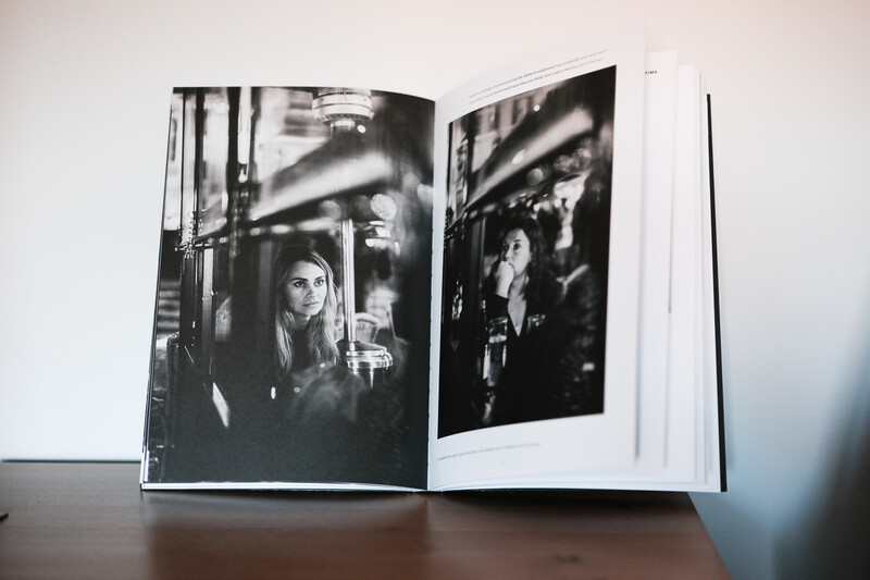Open photobook displaying black and white portrait photographs with dramatic overhead lighting and shadows.