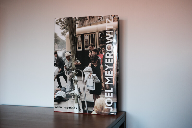 Hardcover photography book displayed upright on a dark surface against a white wall.