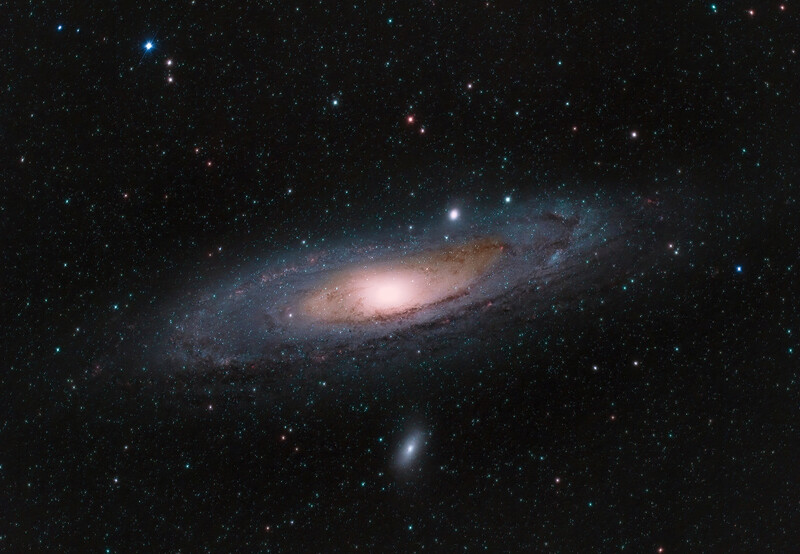 Andromeda galaxy photographed against a starfield, showing spiral disk with bright nucleus and dust lanes.