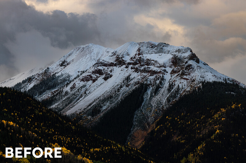 Snow-covered mountain peak with forested lower slopes under dramatic cloudy sky.