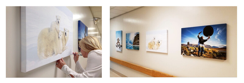 Person adjusting printed photographs mounted on a white gallery wall.