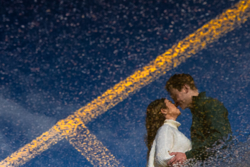 Couple embracing under a starry night sky with golden light streaks overhead.
