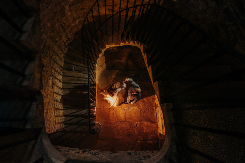 Two people silhouetted by warm firelight inside a brick kiln or oven viewed from above.